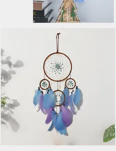 Dettaglio dell'acchiappasogni artigianale con piume blu viola e luci LED calde
