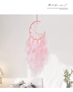 Detail of pink moon dreamcatcher with feathers and beads on a cozy white wall