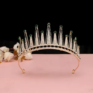Dettaglio ravvicinato di corona da sposa dorata con gemme verde smeraldo e strass bianchi