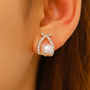 Gros plan de boucles d'oreilles perles et cristaux au design croisé sur l'oreille