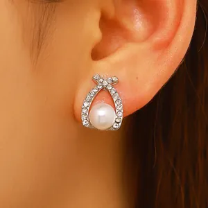 Gros plan de boucles d'oreilles perles croisées avec des accents de zircon brillants