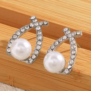 Vue macro détaillée de boucles d'oreilles perles avec bordure en strass argentés