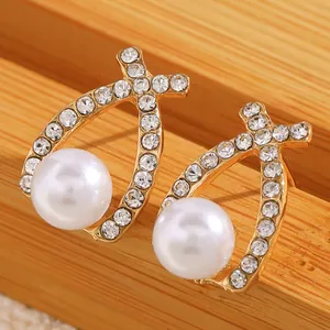 Vue macro de boucles d'oreilles dorées en goutte avec cristaux et perle blanche