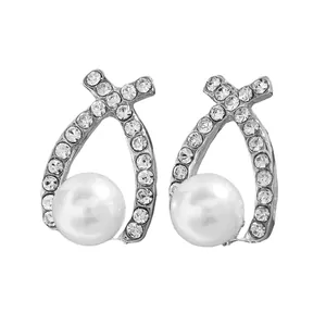 Détail de boucles d'oreilles croisées argentées avec cristaux brillants et perle