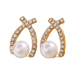 Détail de boucles d'oreilles croisées dorées avec perles blanches et oxydes de zirconium