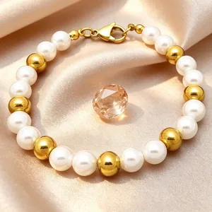 Detailed shot of elegant 8mm pearl and gold stainless steel bead bracelet on champagne silk