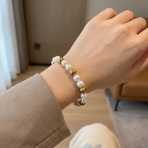 Detail of elegant beaded bracelet with pearls and golden steel beads on wrist