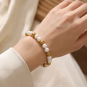 Elegant 8mm white pearl and polished gold steel bead bracelet worn on woman wrist