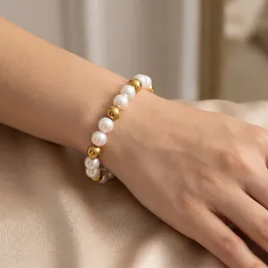 Detailed shot of 8mm white pearls and polished gold steel beads on an elegant bracelet
