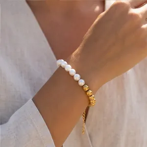 Detail of elegant gold bead and white pearl bracelet with adjustable chain on wrist