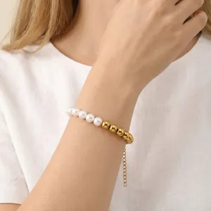 Detail of 8mm pearl and gold stainless steel bead spliced bracelet on a model's wrist