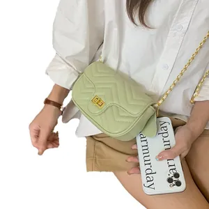 Detail of light green chevron quilted crossbody bag with golden chain and twist lock