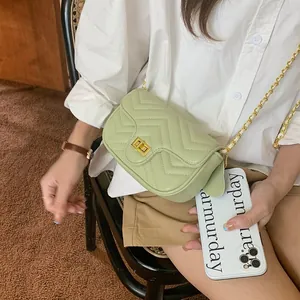 Detail view of mint green quilted crossbody bag with gold chain strap on model
