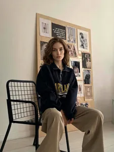 Navy blue half-zip sweatshirt with yellow letters paired with beige wide-leg trousers