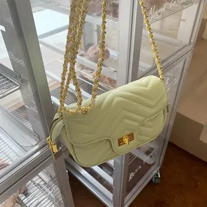 Detail of mint green quilted crossbody bag with gold hardware and chain strap