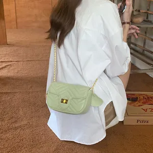 Detail of light green V-quilted faux leather bag with golden chain strap and twist lock