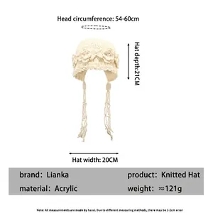 White hand-woven knit beanie with hollow crochet flower patterns and beaded tassels