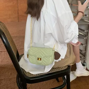Chic light green crossbody bag with V-shaped quilting and gold chain strap on a model