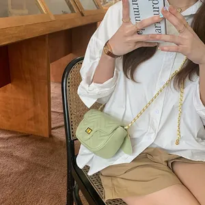 Detailed view of light green quilted crossbody bag with gold chain strap and metal lock