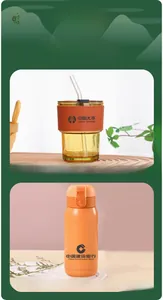 Detail of amber glass coffee cup with leather sleeve and orange stainless steel vacuum flask