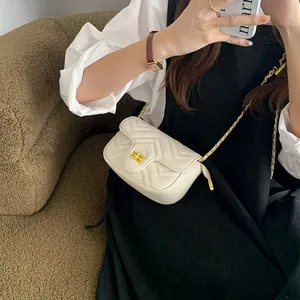 Close-up of beige quilted crossbody bag with golden metal clasp and chain strap