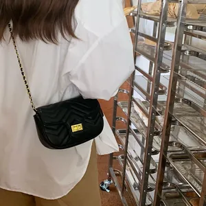 Detail of a black quilted chain crossbody bag with a gold metal turn-lock closure