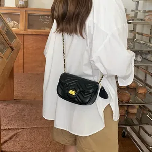 Close-up of black quilted leather crossbody bag with gold hardware and heart charm