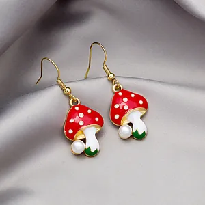 Creative mushroom drop earrings with red caps and white pearls on silk background