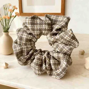 Close-up of elegant houndstooth fabric scrunchie on a marble surface with warm lighting