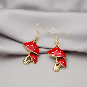 Macro shot of red mushroom earrings with gold spots on a soft grey silk background