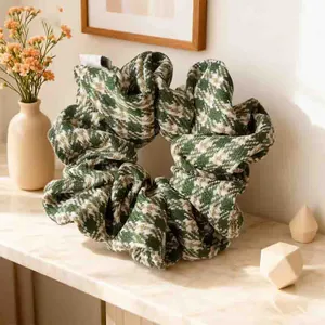Macro detail of oversized dark green houndstooth scrunchie on a marble surface