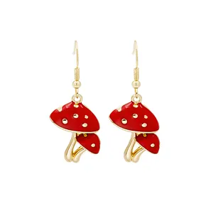 Close-up of cute red mushroom drop earrings with golden hooks and enamel finish