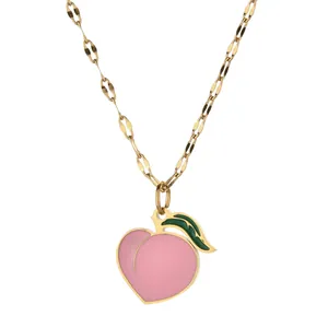 Detailed macro view of peach pendant necklace with pink enamel and gold chain