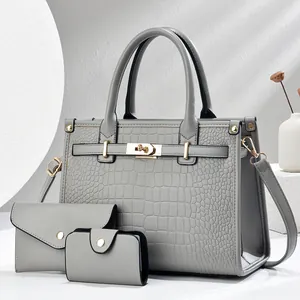 Detailed close-up of grey crocodile embossed leather handbag set with gold hardware