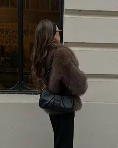 Dettaglio borsa sottobraccio in pelle nera plissettata con cappotto in finta pelliccia