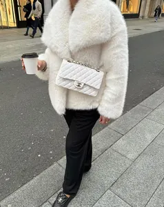 Dettaglio cappotto in pelliccia sintetica bianca con borsa a catena e mocassini neri