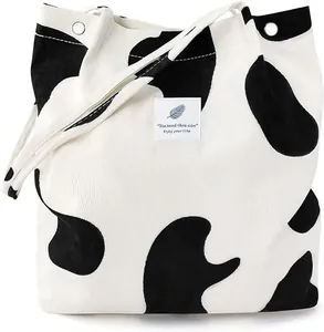 Detail of corduroy tote bag with black and white cow print and text label