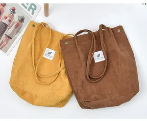 Detailed texture of corduroy tote bags with reinforced metal buckles and fabric labels