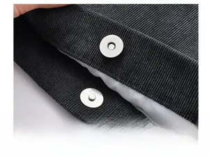 Detail view of the hidden magnetic button on black corduroy tote bag with soft inner lining
