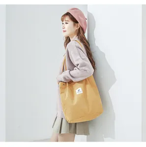 Detail of yellow corduroy tote bag featuring a white botanical patch and side snap button