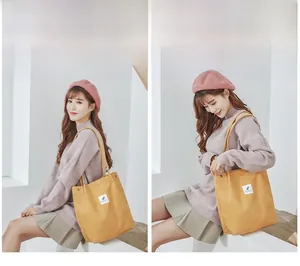 Detail of yellow corduroy tote bag featuring large capacity and a minimalist label design