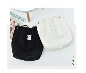 Detailed close-up of corduroy tote bags in black and white with metal snap fasteners