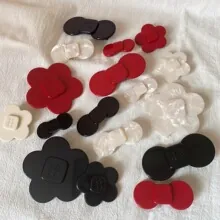 Collection of stylish acrylic bow and flower hair clips in vibrant red, black, and cream.