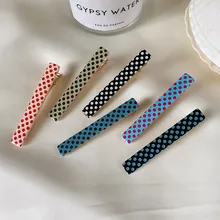 Collection of six vibrant polka-dot hair clips displayed on elegant fabric texture