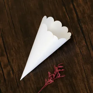 Close-up detail of a white scalloped edge paper cone for wedding confetti on a wood surface