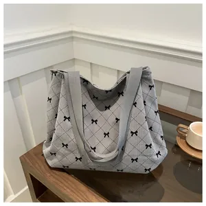 Detailed view of grey corduroy tote bag featuring black bow patterns and grid