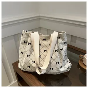 Close-up detail of cream corduroy tote bag featuring elegant black bow and diamond pattern
