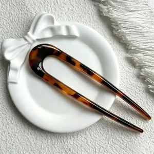 Macro view of a stylish tortoise shell U-shaped hair fork on a decorative plate