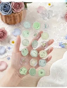 Detailed view of translucent wax seal stickers with floral patterns held by hand.
