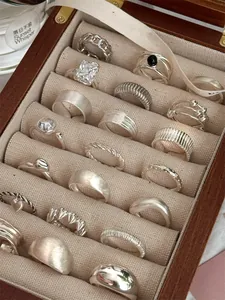 Detailed view of various vintage S925 sterling silver rings in a wooden jewelry box.